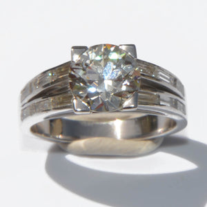 Bague solitaire ornée d'un diamant épaulée de diamant taille baguette